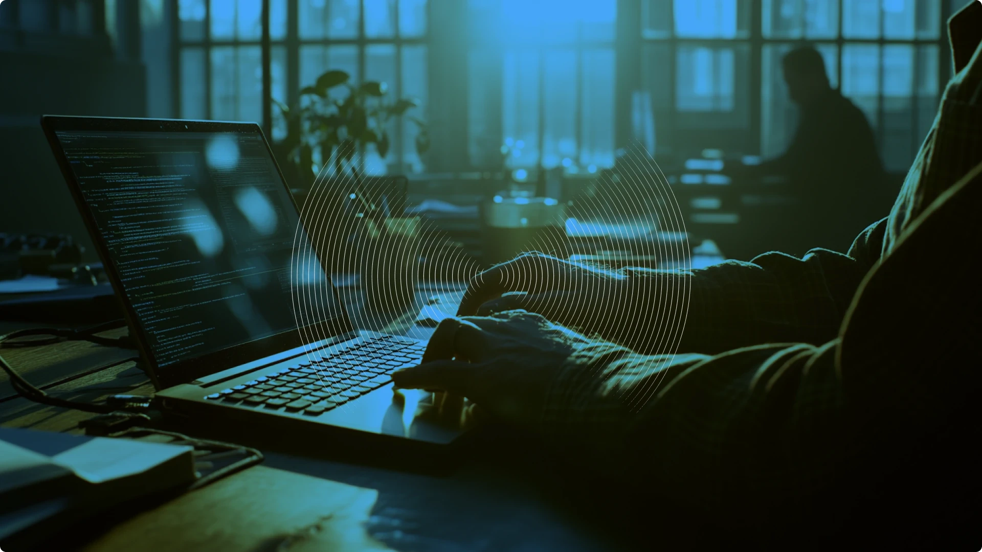 Person working on a laptop with code, in a dimly lit office environment.