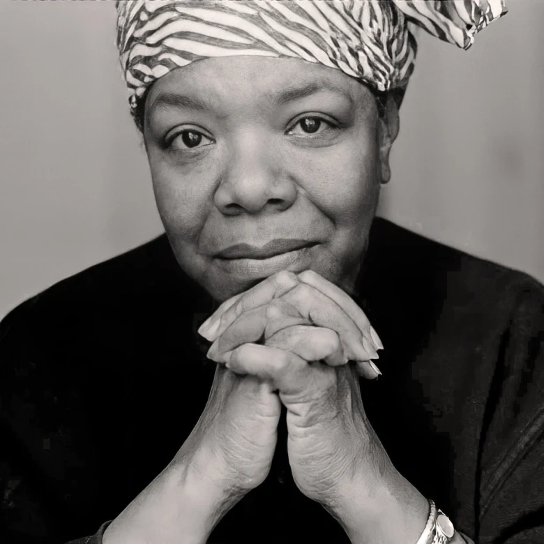 A woman wearing a headscarf, resting her chin on her clasped hands, looking directly at the camera.